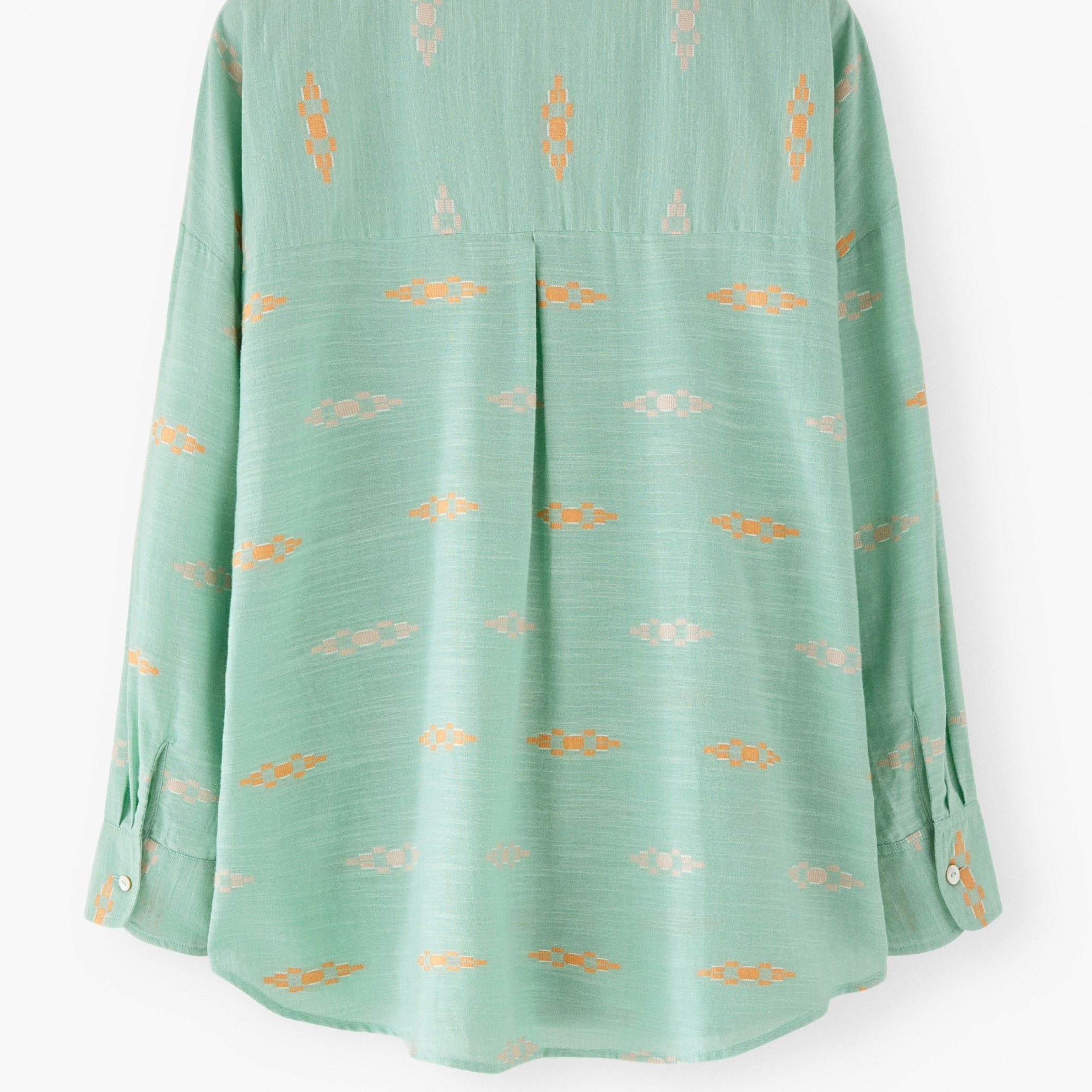 Green blouse with gold patterns on a white background