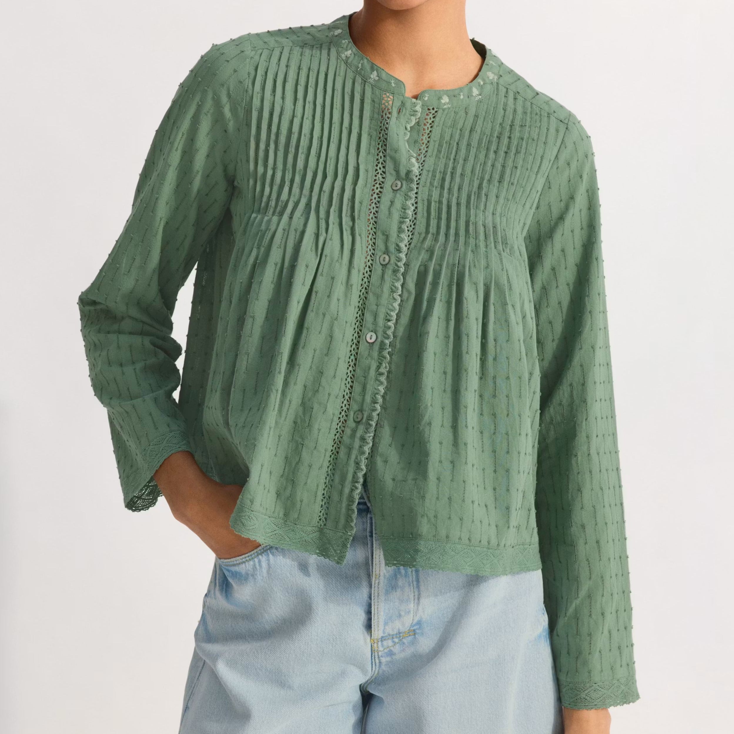 Woman wearing a green textured shirt and denim shorts on a white background