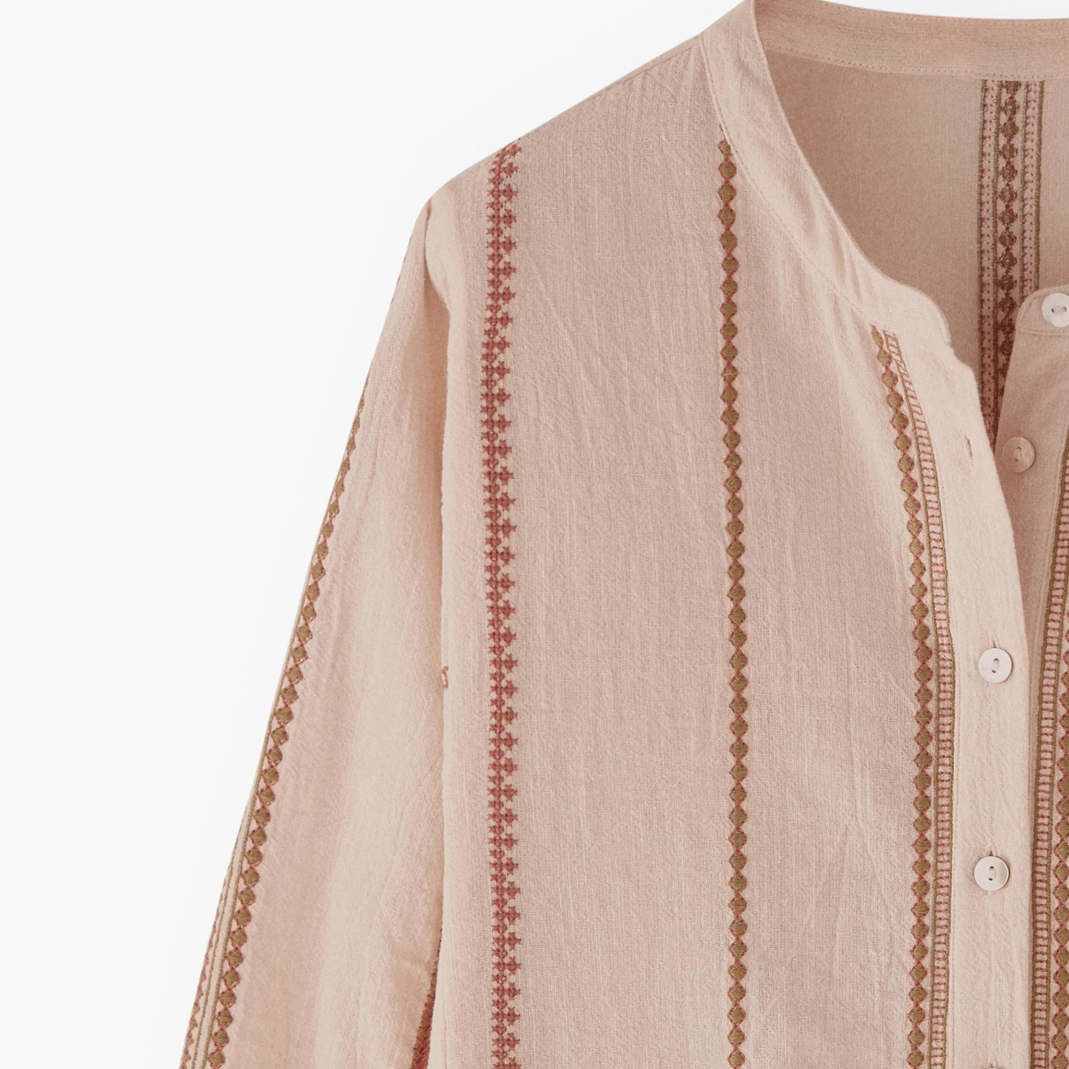Beige shirt with intricate embroidery on a white background