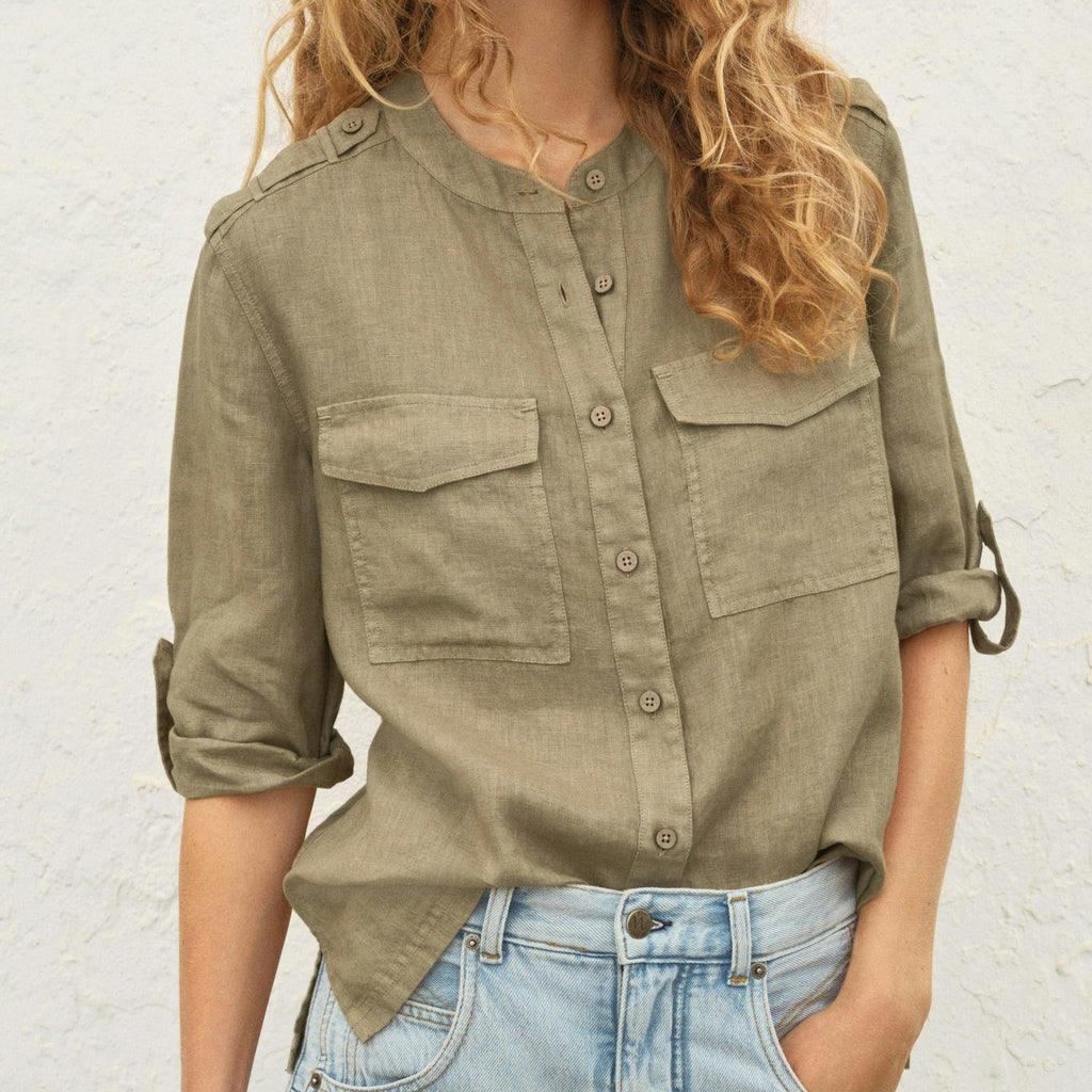 Woman wearing a green shirt and blue jeans against a white wall